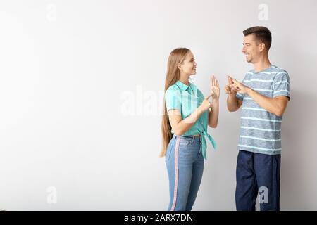 Giovane coppia sordomuta utilizzando il linguaggio dei segni su sfondo bianco Foto Stock