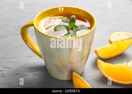 Tazza di tè caldo con fettine di frutta arancione su sfondo grigio Foto Stock