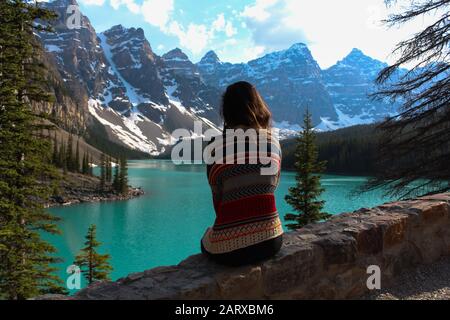 Dopo una breve escursione sulla montagna. È stato in grado di catturare questa splendida foto. Di una ragazza che indossa un maglione indiano mentre si affaccia sul lago Moraine Banff. Foto Stock