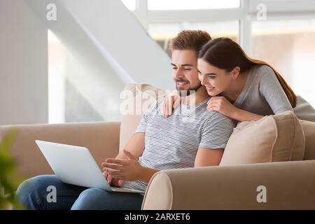 Ritratto di bella giovane coppia con il portatile a casa Foto Stock