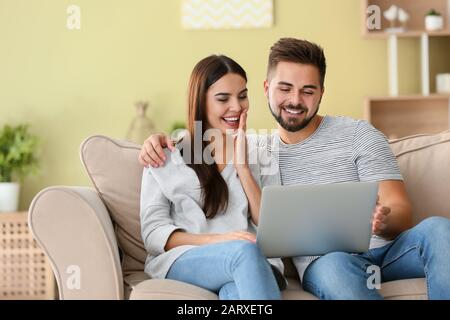 Ritratto di bella giovane coppia con il portatile a casa Foto Stock