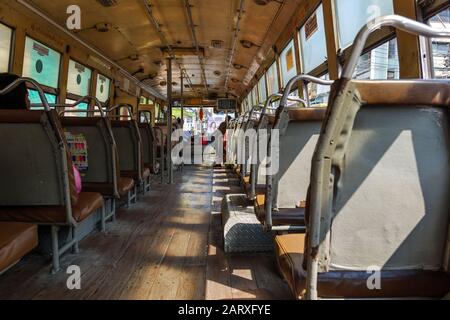 Vista interna del corridoio tra la fila di posti a sedere in un vecchio autobus pubblico caldo locale senza aria condizionata a Bangkok, Thailandia. Foto Stock