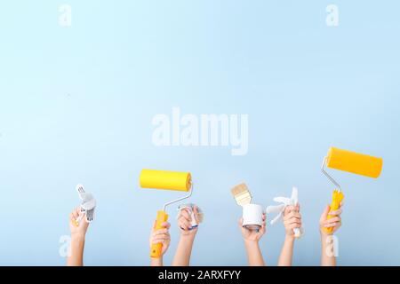 Mani femminili con strumenti per pittore su sfondo colorato Foto Stock