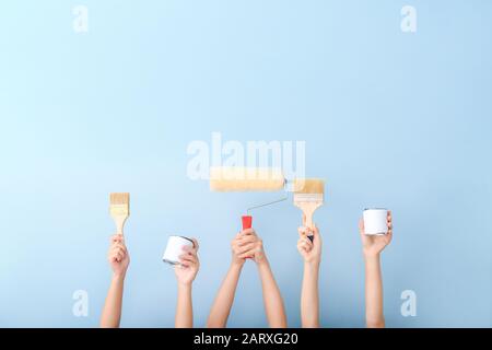 Mani femminili con strumenti per pittore su sfondo colorato Foto Stock