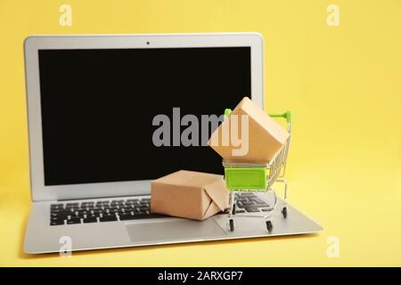 Shopping su Internet. Piccolo carrello con scatole e moderno computer  portatile sul tavolo al coperto, spazio per il testo Foto stock - Alamy