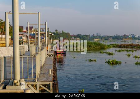 Vista tranquilla di Long tail barca ancora accanto galleggianti pontone in acciaio, molo o molo senza persone e galleggiante acqua hyacinth sul fiume Chao Phraya. Foto Stock