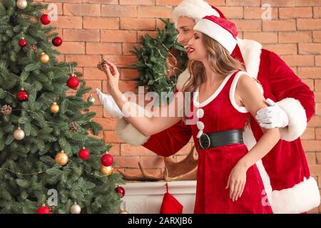 Giovane coppia vestita come Babbo Natale decorazione Natale a casa Foto Stock