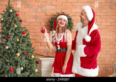 Giovane coppia vestita come Babbo Natale decorazione Natale a casa Foto Stock