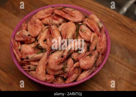 gamberetti. Gamberi bolliti in un piatto. Gamberi bolliti su una tavola di legno in cucina. Gamberetti in un piatto di plastica rosa. Dieta proteica Foto Stock