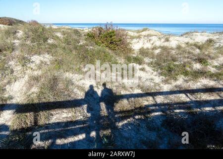 Ritratto astratto di una coppia ombra su una passerella sulle dune di sabbia su Jekyll Island, Georgia, USA, una tranquilla destinazione di viaggio lento. Foto Stock