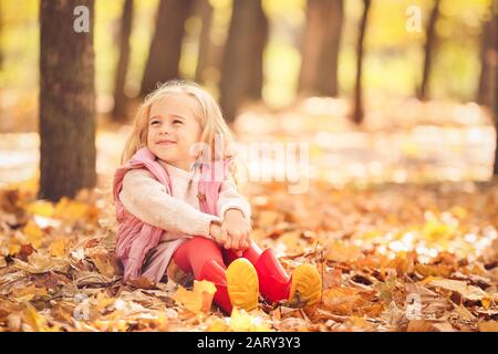 Ragazza carina seduta nel parco autunnale Foto Stock