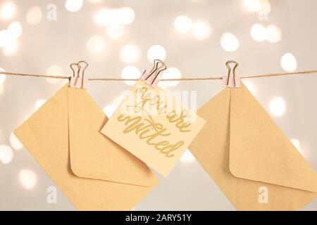 Invito con buste appese su corda su sfondo chiaro Foto Stock