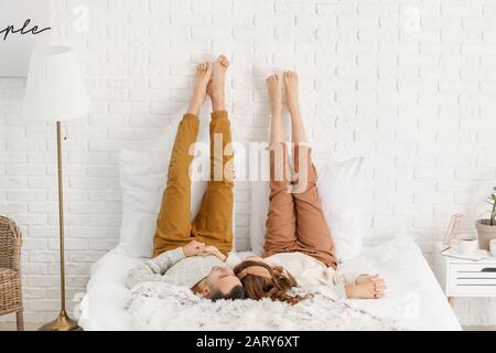 Bella coppia giovane sdraiata a letto a casa Foto Stock