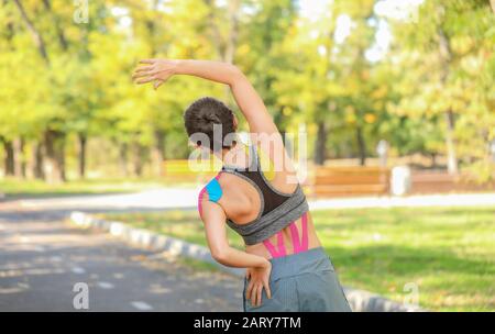 Donna sportiva con nastro fisio applicato sulla schiena all'aperto Foto Stock