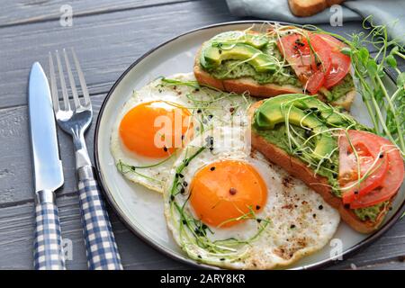 Piatto con gustosi sandwich di avocado e uova fritte sul tavolo Foto Stock