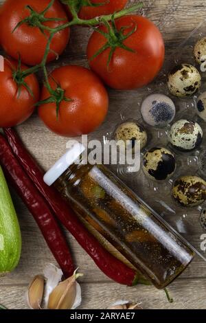 Posando gli ortaggi in tavola, la composizione è composta da uova di quaglia, pomodori, zucchine, spinaci e olio d'oliva. Foto Stock