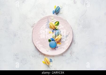 Piatto con diversi macaron gustosi su sfondo bianco Foto Stock