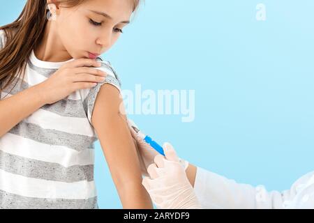 Medico vaccinare la bambina su sfondo chiaro Foto Stock