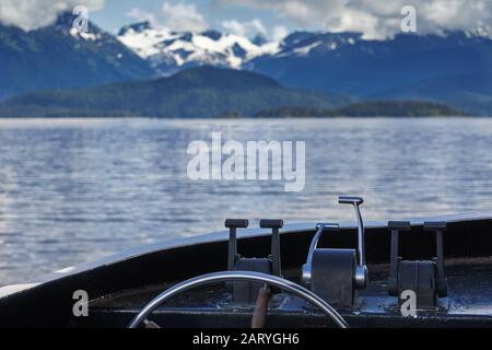 Una piccola barca si sta avvicinando a un ghiacciaio. Ruota dell'imbarcazione a fuoco. Escursione con avvistamento di balene a Juneau, Alaska. Cime di neve sullo sfondo. Foto Stock