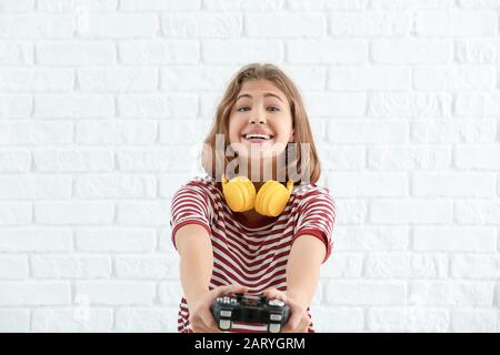 Ragazza adolescente con game pad su sfondo bianco mattone Foto Stock