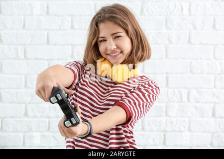 Ragazza adolescente con game pad su sfondo bianco mattone Foto Stock