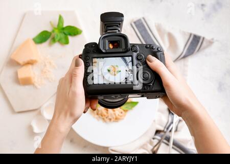 Fotografo femminile che fotografa la pasta sul tavolo Foto Stock