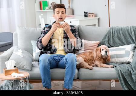 Giovane uomo che soffre di allergia dell'animale domestico nel paese Foto Stock