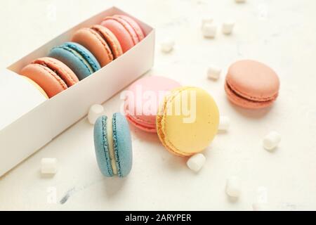Scatola con diversi macaron gustosi e marshmallows su sfondo bianco Foto Stock