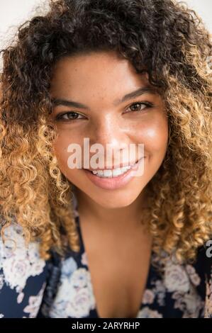 Donna sorridente con capelli ricci Foto Stock