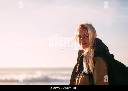 Donna sorridente che indossa lo zaino dal mare Foto Stock