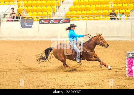 Lady rider si avvicina a un barile in un'arena al coperto in Tamworth Australia. Foto Stock