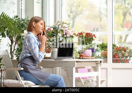 Fioraio tenendo ordinare per telefono in negozio Foto Stock