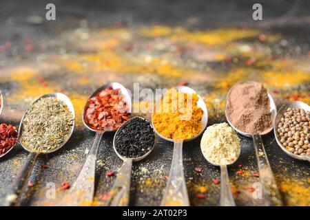 Cucchiai con spezie diverse su sfondo scuro Foto Stock