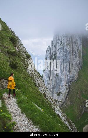 Donna che indossa una giacca gialla in montagna ad Appenzell, Svizzera Foto Stock