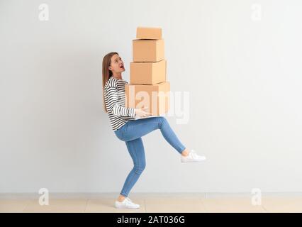 Donna importunata con scatole in movimento vicino alla parete della luce Foto Stock