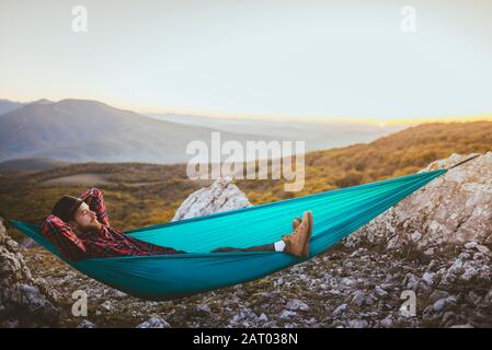 Uomo sdraiato su amaca in catena montuosa Foto Stock