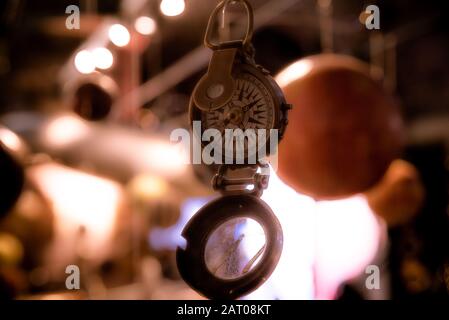 Bellissimo bokeh di fondo di una bussola appeso con luci e riflessioni in background. Concetto di essere perduti, libertà e ricerca della felicità. Foto Stock