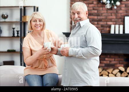 Coppia matura felice che beve cioccolata calda a casa Foto Stock