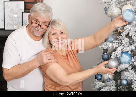 Coppia matura felice che decorano l'albero di Natale a casa Foto Stock
