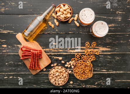 Composizione con birra fresca e spuntini su sfondo di legno Foto Stock