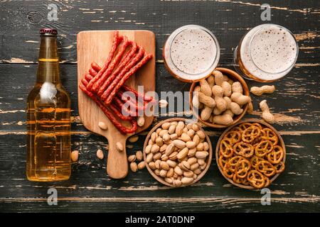 Composizione con birra fresca e spuntini su sfondo di legno Foto Stock