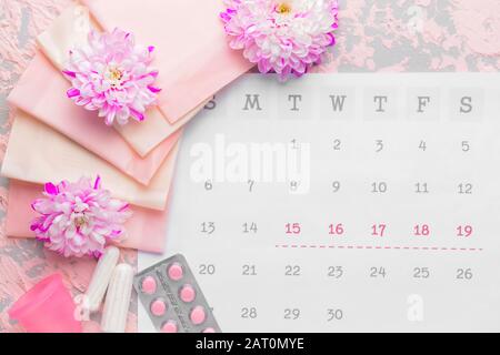 Calendario mestruale femminile con prodotti e pillole sul colore di sfondo Foto Stock