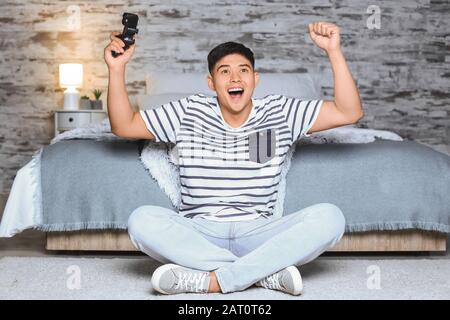 Uomo asiatico che gioca a casa in serata Foto Stock