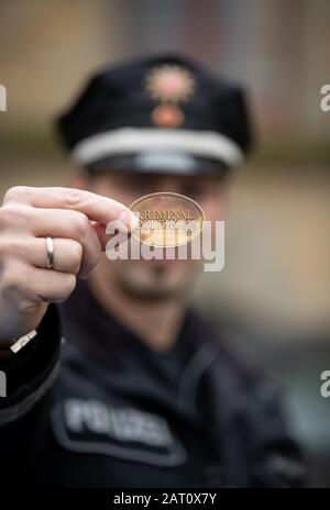 Illustrazione - 24 gennaio 2020, Bassa Sassonia, Osnabrück: Un ufficiale di polizia tiene in mano un distintivo del dipartimento di investigazione penale. I badge, così come i badge, possono identificare gli agenti di polizia portando un numero di badge specifico. Succede sempre che i truffatori fingano di essere "falsi poliziotti", soprattutto con gli anziani. Foto: Friso Gentsch/Dpa Foto Stock