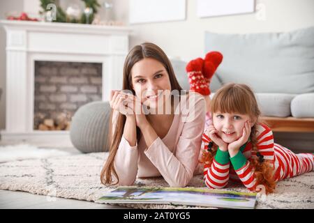 Bambina con libro di lettura madre a casa Foto Stock