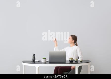 Giovane donna che lavora in ufficio con condizionatore d'aria funzionante Foto Stock