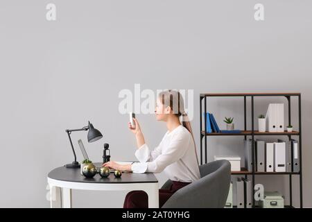 Giovane donna che lavora in ufficio con condizionatore d'aria funzionante Foto Stock