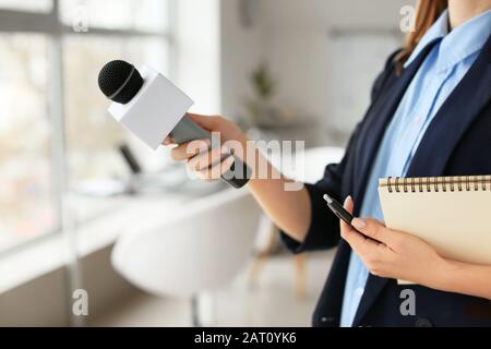 Giornalista femminile con microfono che ha un'intervista in ufficio Foto Stock