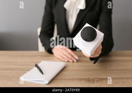 Giornalista femminile con microfono che ha un'intervista in ufficio, primo piano Foto Stock