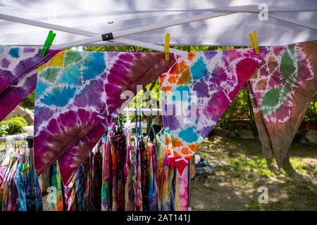 Prodotti colorati di tie e coloranti in vendita in un negozio hippie al mercato contadino locale. Primo piano di un filo sospeso con tovaglioli colorati appesi con chiodi di garofano Foto Stock